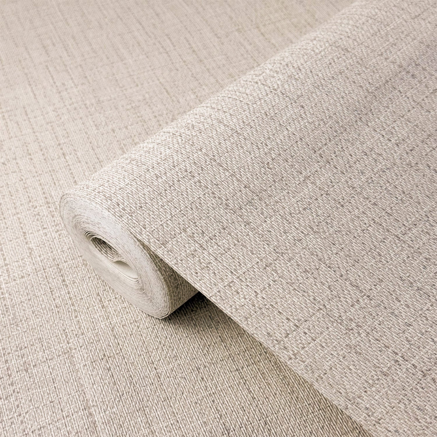 A close-up of a rolled piece of textured fabric or wallpaper in a warm light beige tone, showing the woven pattern and thickness.